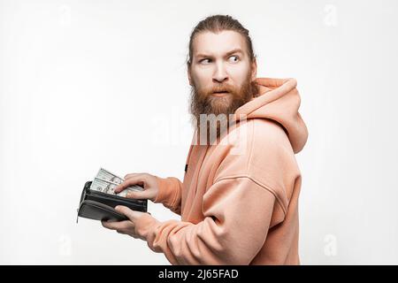 Handsom homme tenant la monnaie papier dans le portefeuille et est malheureux sur fond gris. Main retirer 100 billets de banque de portefeuille. Guy ont de l'argent. Le con Banque D'Images