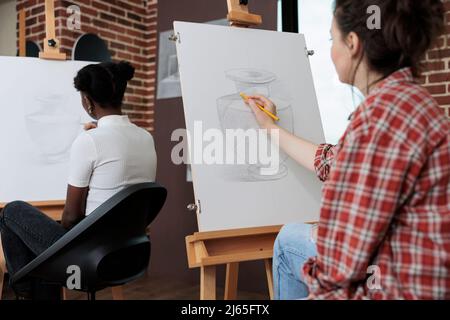 Jeune étudiant dessin vase artistique sur toile de peinture travailler à la technique d'illustration en utilisant le crayon graphique pendant la leçon d'art en studio de créativité. Équipe multiethnique développant des compétences créatives Banque D'Images