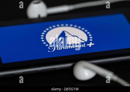 Rheinbach, Allemagne 28 avril 2022, le logo du service de streaming « Paramount + » sur l'écran d'un smartphone avec casque Banque D'Images