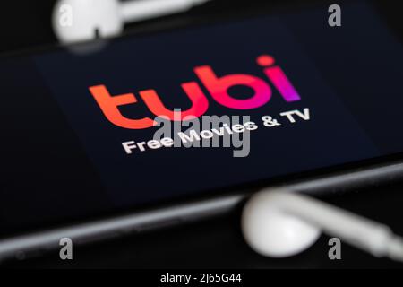 Rheinbach, Allemagne 28 avril 2022, le logo de la marque du service de streaming « Tubi » sur l'écran d'un smartphone avec casque Banque D'Images