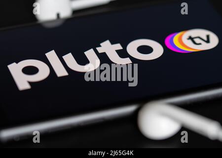 Rheinbach, Allemagne 28 avril 2022, le logo de la marque du service de streaming « Pluton TV » sur l'écran d'un smartphone avec casque Banque D'Images