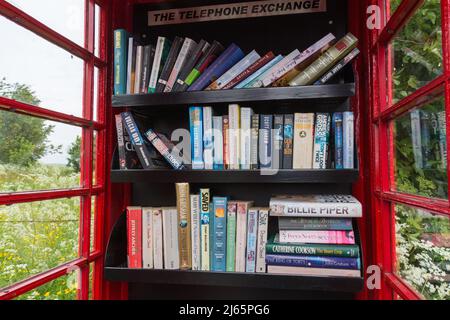 Échange de livres dans une ancienne boîte téléphonique rouge Banque D'Images