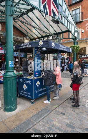 Les gens font la queue pour acheter de la nourriture dans la rue grecque de M. à l'extérieur du Jubilee Market Hall à Covent Garden, Londres, Angleterre, Royaume-Uni Banque D'Images