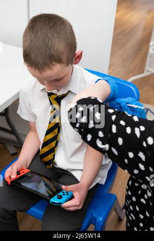 USAGE ÉDITORIAL SEULEMENT Luca Stephenson, huit ans, de Maidstone, l'un des premiers enfants du groupe d'âge de 5 à 11 ans à recevoir le vaccin Pfizer BioNTech, au centre de vaccination Covid-19 de Pharmacy2U, Maidstone, Kent. Date de publication : jeudi 28 avril 2022. Banque D'Images