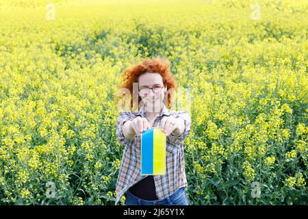 Une femme à tête rouge qui porte un drapeau ukrainien Banque D'Images