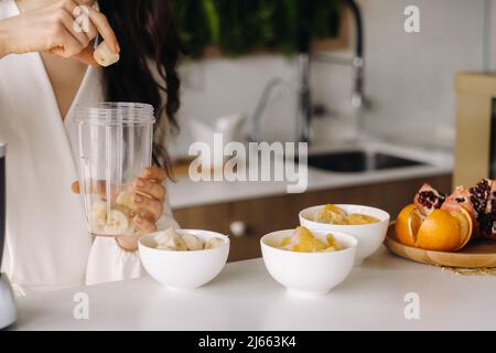 Gros plan des mains d'une fille qui fait un cocktail de fruits détox dans la cuisine. Régime pour la perte de poids. Banque D'Images