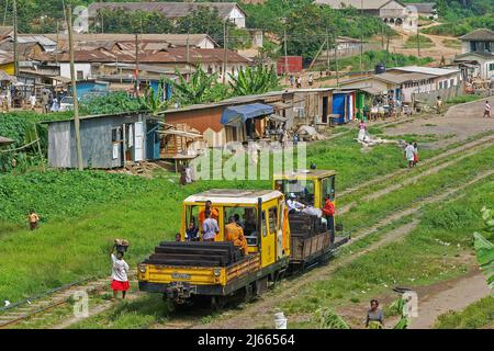 Ghana - chemin de fer entre Accra et la ville portuaire de Tacoradi. Les gens se promou par-dessus la voie pendant qu'une locomotive de maintenance vérifie les rails. Banque D'Images