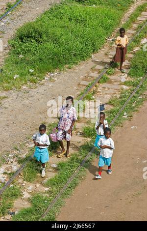 Ghana - chemin de fer entre Accra et la ville portuaire de Tacoradi. Les gens se promou par-dessus la voie pendant qu'une locomotive de maintenance vérifie les rails. Banque D'Images