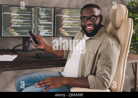 Portrait de beau gai gai expérimenté gars geek freelance utilisant le gadget au poste de travail à l'intérieur Banque D'Images