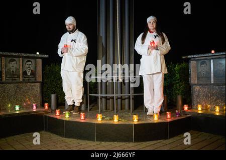 Slavutych, Ukraine. 26th avril 2022. Des artistes ont vu tenir des bougies devant le Monument aux héros décédés de Tchernobyl. Le 36th anniversaire de la catastrophe à la centrale nucléaire de Tchernobyl a eu lieu le 26th 1986 avril (à 01.23.40 heures), a été commémoré par une cérémonie publique à Slavutych (Ukraine), une ville satellite construite après la catastrophe, accueillant principalement les travailleurs de la centrale. Crédit : SOPA Images Limited/Alamy Live News Banque D'Images