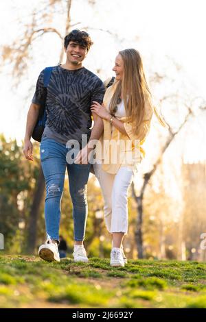Jeune couple hétérosexuel marchant dans un parc et parlant Banque D'Images