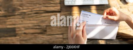 Close-up de l'homme d'affaires d'ouverture de l'enveloppe avec un chèque en bois de plus de 24 Banque D'Images
