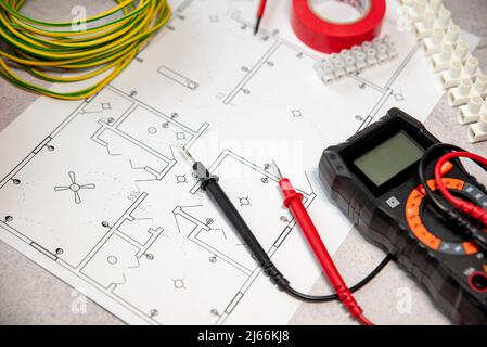 Multimètre, différents outils et matériaux pour l'électricien et le câble a coulé sur le plan d'électrification de la maison. Banque D'Images