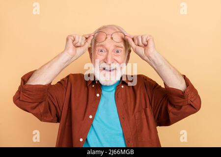 Photo d'un homme gris élégant et impressionné coiffure look caméra porter des lunettes marron chemise isolée sur fond beige couleur Banque D'Images