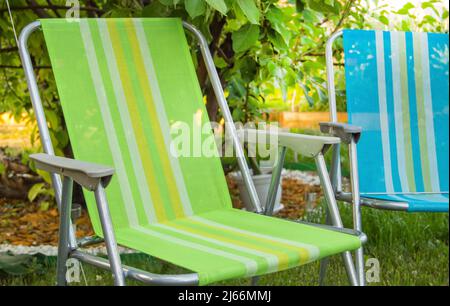 Deux chaises pliantes de jardin se tiennent à l'ombre sous un arbre lors d'une chaude journée d'été dans le jardin, en gros plan. Banque D'Images