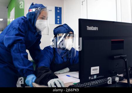 Tyumen, Russie, 14.07.2021. Les travailleurs médicaux ou les médecins sous masques et vêtements de protection peuvent consulter les données en ligne sur un ordinateur dans la base de données de la clinique. Banque D'Images