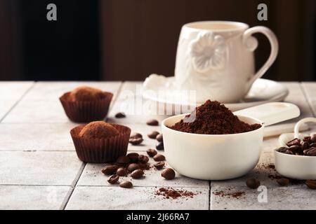 Fond de café. Cuillères à mesurer avec du café moulu, des haricots, une tasse et des truffes au chocolat doux sur un fond de table vieux carrelage fissuré. La nourriture. Banque D'Images