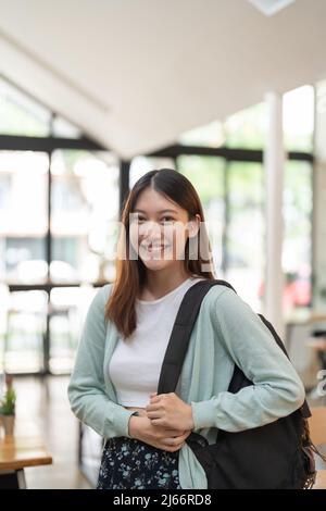 Portrait jeune femme asiatique étudiant tenant une tablette numérique à l'université debout devant un casier avec sac à dos. Banque D'Images