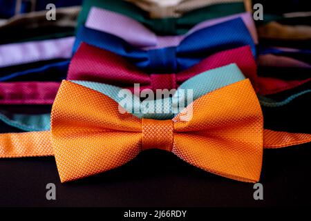 Noeuds colorés disposés dans une rangée, cravate orange sur le devant, vêtements homme accessoire mode concept, sélectif focus, gros plan Banque D'Images