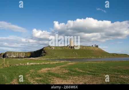 Vue sur le château de Dunstanburgh depuis la promenade côtière et les dunes au bord du parcours de golf Banque D'Images