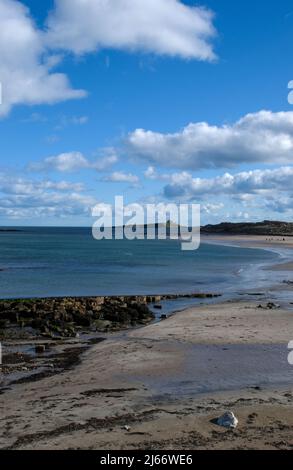 Image de style portrait d'une longue plage de courbure s'étendant de Low Newton à un château de Dunstanburgh lointain dans Northumberland Banque D'Images