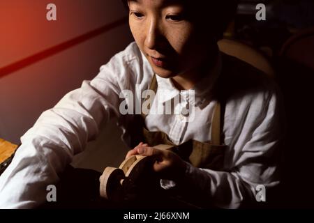 Jeune violoniste chinoise travaillant sur le cou du violon en construction dans son atelier Banque D'Images