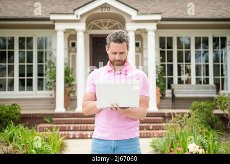 homme barbu occupé agent immobilier vendant ou louant la maison en ligne sur ordinateur, courtier Banque D'Images