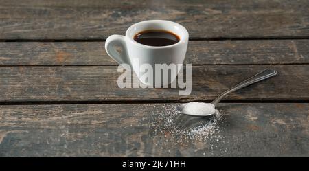 Café noir chaud ou espresso dans une tasse en céramique blanche sur fond de texture bois. À côté d'une cuillerée de sucre Banque D'Images