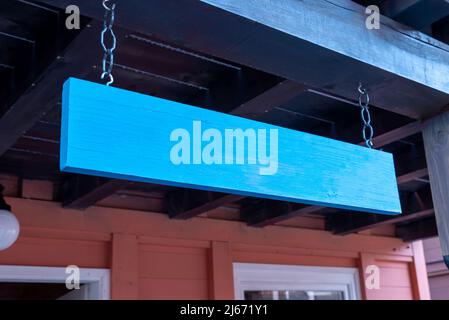 Panneau en bois bleu suspendu à l'entrée du magasin. Nettoyer la surface pour la présentation du logo ou du nom Banque D'Images