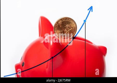 Graphique de croissance, renforcement du dollar américain. Coin 1 lolar dans un trou dans une banque de porc rouge sur un fond blanc avec un graphique. Concept d'économies Banque D'Images