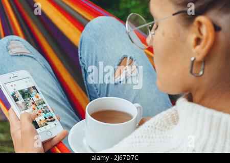 Jeune femme utilise un smartphone pour les médias sociaux. Jeune fille jeune fille regarde la galerie de photos affichée sur les médias sociaux. Adult Girl influenceur parcourant pictur Banque D'Images