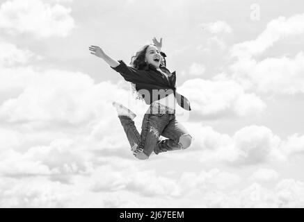 un enfant souriant sautant. insouciant et joyeux. style de mode pour les enfants. une adolescente sur fond de ciel à l'extérieur. un saut pour les enfants à l'arrière-plan. une bonne journée pour les enfants Banque D'Images