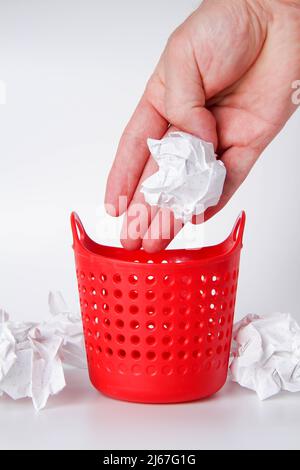 La main place les déchets dans le panier. Nettoyage du lieu de travail. Un homme nettoie le bureau. Banque D'Images