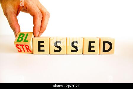Symbole béni ou stressé. L'homme d'affaires tourne des cubes en bois et change le mot concept souligné à Blessed. Magnifique table blanche fond blanc. B Banque D'Images