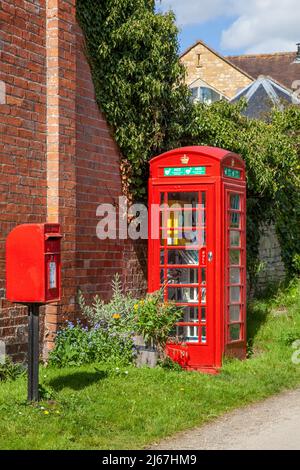 La boîte postale rouge anglaise et le kiosque téléphonique servent maintenant d'échange de livres et d'hébergement du défibrillateur du village dans le hameau de Grafton Worcestershire Banque D'Images