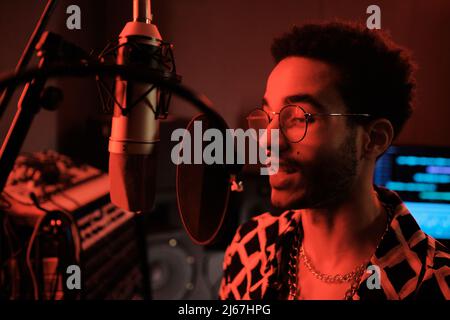 Portrait d'un jeune chanteur noir travaillant dans un studio d'enregistrement devant la chanson de chant du microphone Banque D'Images