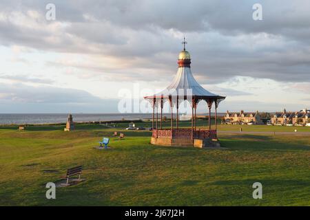 Lumière du soleil en soirée sur le Wallace Bandstand, construit en 1884. Moray Firth, Nairn Links, Fishertown et le port de plaisance en arrière-plan. Banque D'Images