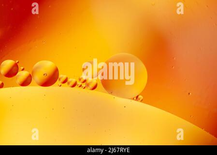 Photographie abstraite de gouttelettes d'huile dans l'eau sur un fond de couleur vive orange, rouge et jaune. Convient aux arrière-plans. Banque D'Images