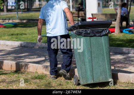 Homme transportant des ordures avec un conteneur à ordures Banque D'Images
