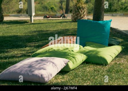 Étudiants assis sur des coussins sous les arbres Banque D'Images