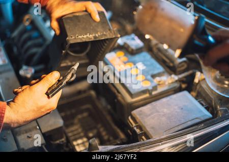 Un mécanicien souffle le compartiment sale du filtre à air avec le compresseur Banque D'Images