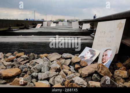 Auschwitz, Pologne. 28th avril 2022. Des photographies des victimes de l'Holocauste sont laissées sur les voies ferrées de l'ancien site d'Auschwitz II-Birkenau. À l'occasion de la Journée internationale de commémoration de l'Holocauste, des participants de différentes parties du monde participent à la marche des vivants. La marche des vivants est un hommage et un symbole de mémoire pour les victimes de l'Holocauste. Les participants à la marche couvrent ensemble le tronçon de trois kilomètres qui mène de la porte d'Arbeit Macht Frei à l'ancien camp allemand d'Auschwitz I à l'ancien site d'Auschwitz II - Birkenau. Crédit : SOPA Images Limited/Alamy Live News Banque D'Images