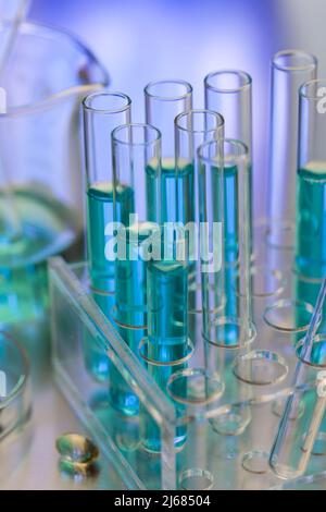 Tubes à essai soigneusement disposés contenant du réactif bleu dans le laboratoire de chimie avec bécher et capsule souple - photo de stock Banque D'Images