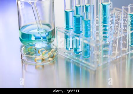 Boîte en verre contenant des capsules molles dans un LABORATOIRE de chimie avec bécher et portoir pour tubes à essai - photo de stock Banque D'Images