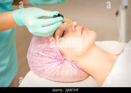 Jeune femme blanche se peler le rétinol organique acide peau avec la pipette dans une clinique de beauté Banque D'Images