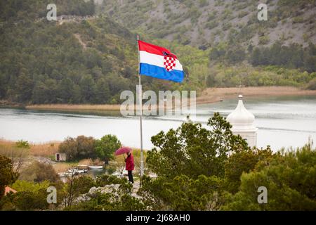 Skradin petite ville du comté de Šibenik-Knin en Croatie, rivière Krka et clocher de l'église de Mala Gospa et drapeau national de la caste Banque D'Images