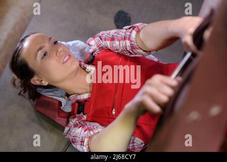 femme mécanicien couché et travaillant sous la voiture Banque D'Images