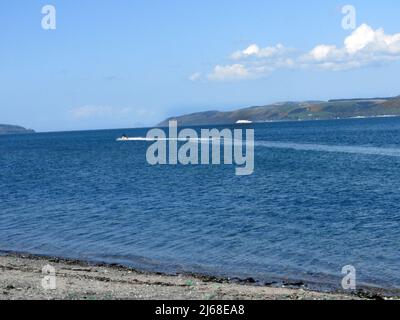 Loch Ryan, un scooter des mers avec Cairnryan ( Machair an Sgithich) et un ferry irlandais en arrière-plan. Banque D'Images