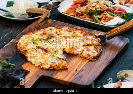 Pizza maison avec des plats asiatiques épicés sur une table en bois Banque D'Images