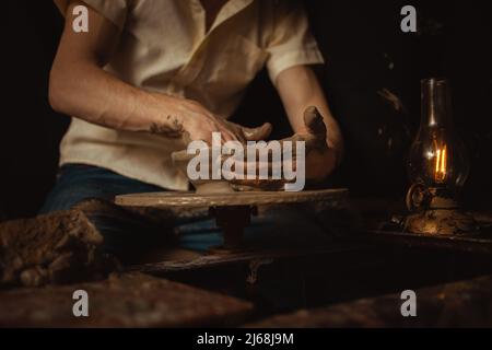 homme dans atelier de poterie fait plaque d'argile, une atmosphère authentique, lampe jaune, style de vie, atmosphère magique. Concept avec vos propres mains, maison fr Banque D'Images